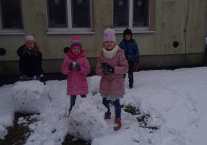 Dzieci lepią dwie duże kule śniegowe